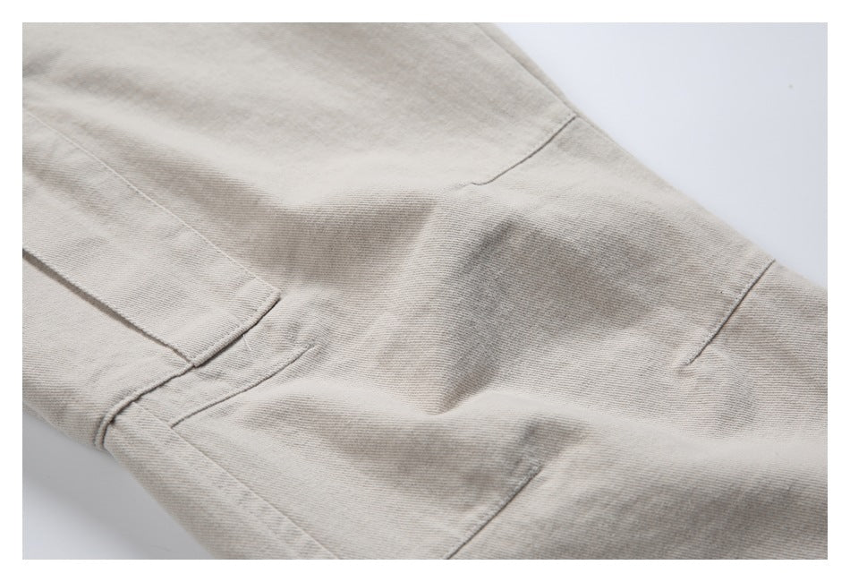 Close-up of beige pants fabric and stitched leg-panel seams.