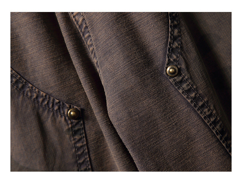 Close-up of brown garment fabric showing double-stitched seams and two brass-tone snap fasteners.