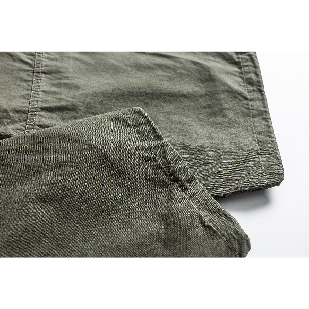 Close-up of olive pant legs showing the fabric texture, seams, and folded hems.