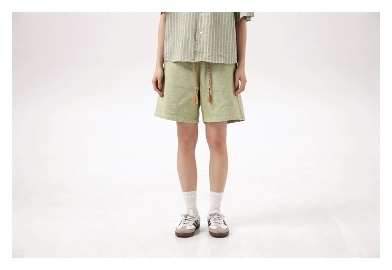 Front view of a model wearing light green drawstring shorts, cropped from the torso down.