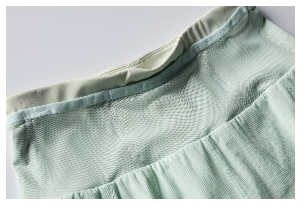 Close-up of a pale mint garment's inner waistband and lining, with gathered stitching below.