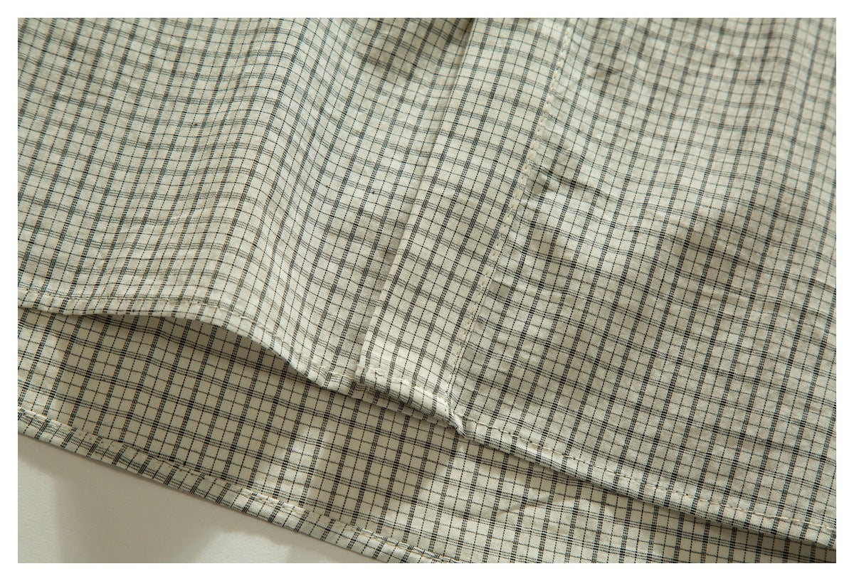 Close-up of the cream plaid shirt fabric, showing a stitched seam and hem edge.