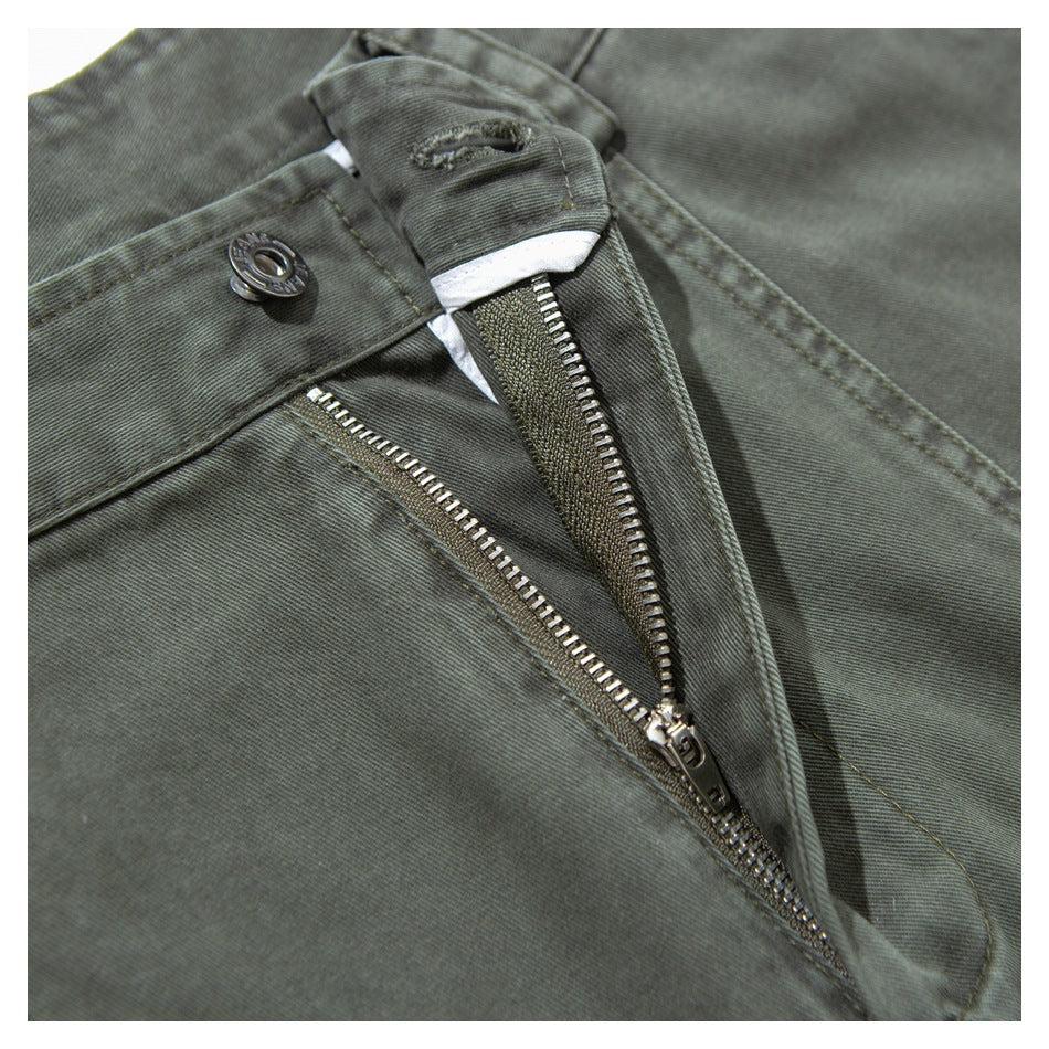 Close-up of olive-gray trousers with the metal zipper fly and waistband button undone.