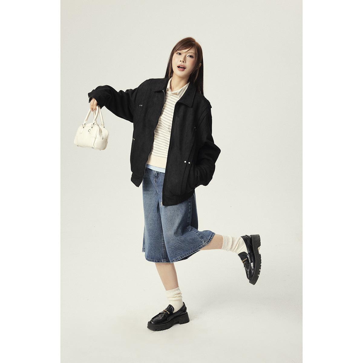 Model wearing an oversized black jacket with a zip front, pointed collar, and gathered hem.