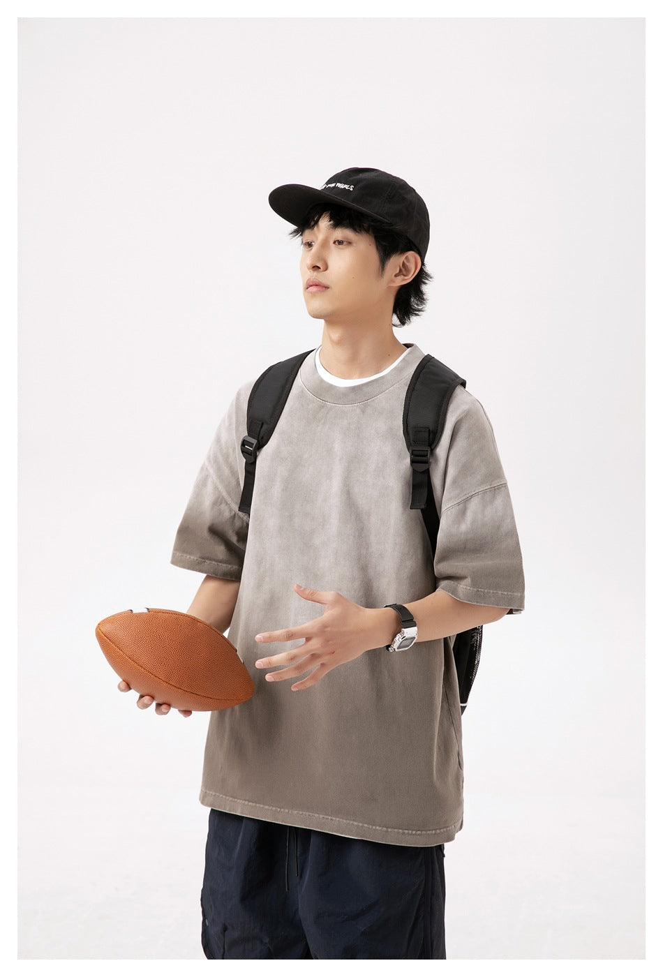 Model wearing an oversized taupe-gray T-shirt with dropped shoulders and a ribbed crew neck.