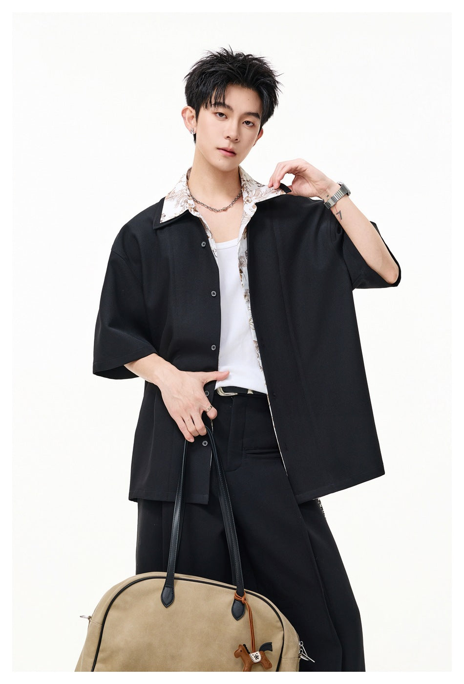 Model wearing a black oversized short-sleeve button-up with a light floral collar over a white tank.