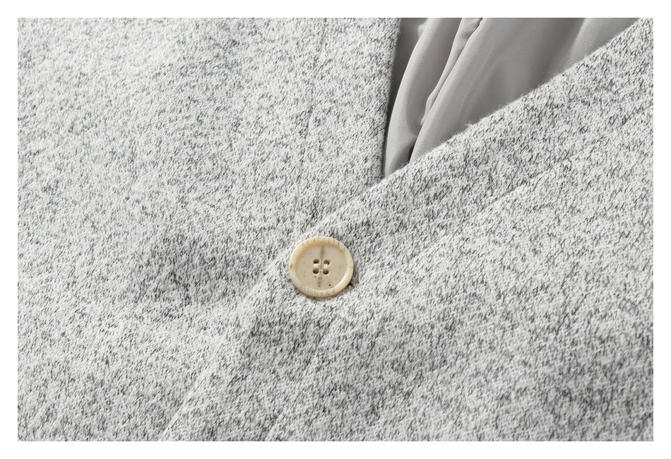 Close-up of a cream four-hole button on a light gray marled knit garment.