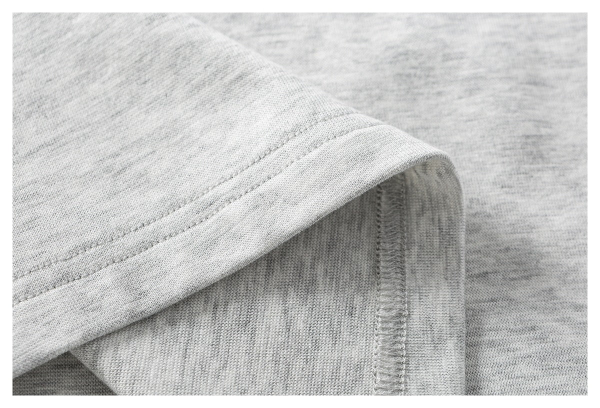 Close-up of a double-stitched hem and overlocked seam on a light gray heathered garment.