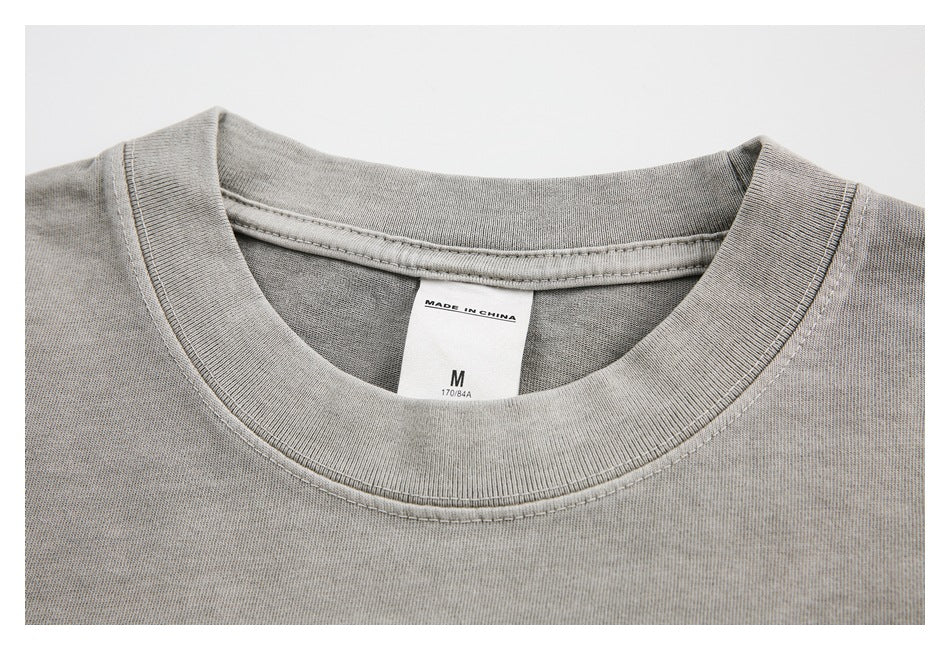 Close-up of the ribbed crew neck and inner label on a light gray washed T-shirt.