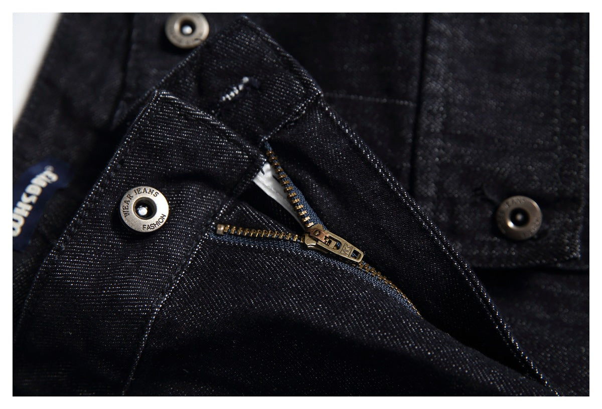 Close-up of black jeans showing an open metal zipper, waistband button and stitching.
