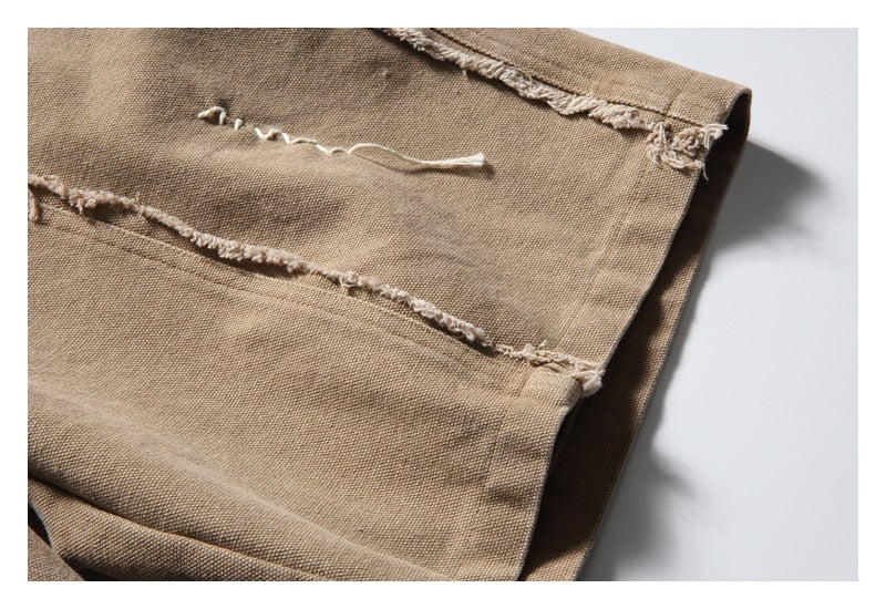 Close-up of tan trousers showing distressed seams and loose white threads.