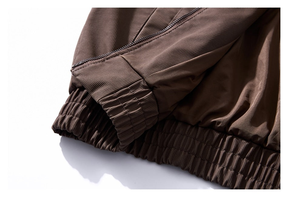 Close-up of a brown jacket showing a zippered sleeve cuff and gathered elastic hem.