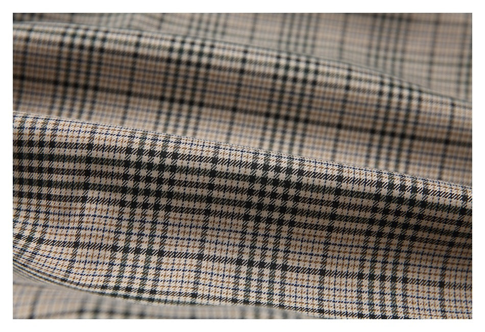Close-up of beige, brown, and black plaid fabric with a fine woven check pattern.