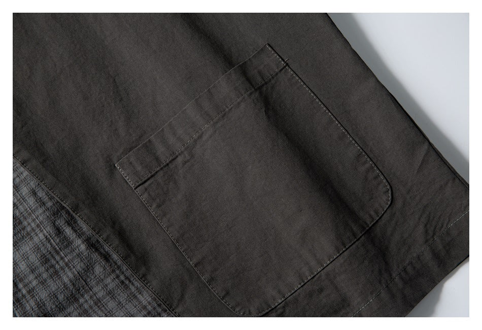 Close-up of a dark charcoal patch pocket beside a section of gray plaid fabric.