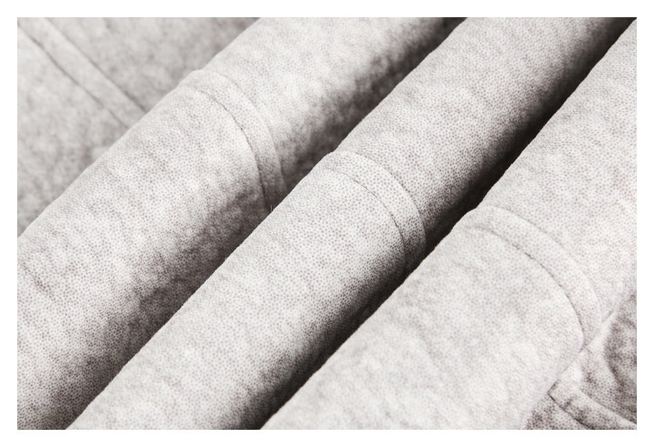 Close-up of the light beige jacket's finely speckled fabric and stitched seams.