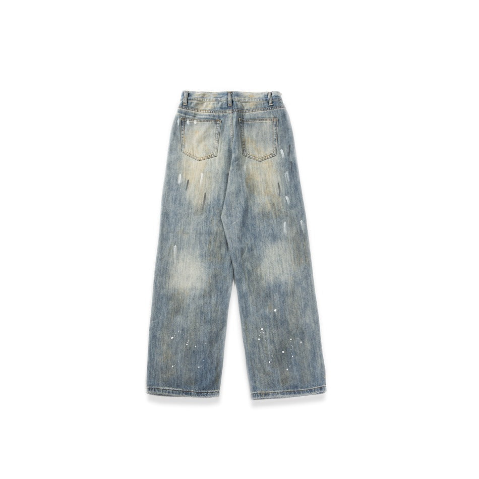 Back view of loose faded blue jeans with two patch pockets and scattered paint-like marks, shown flat.