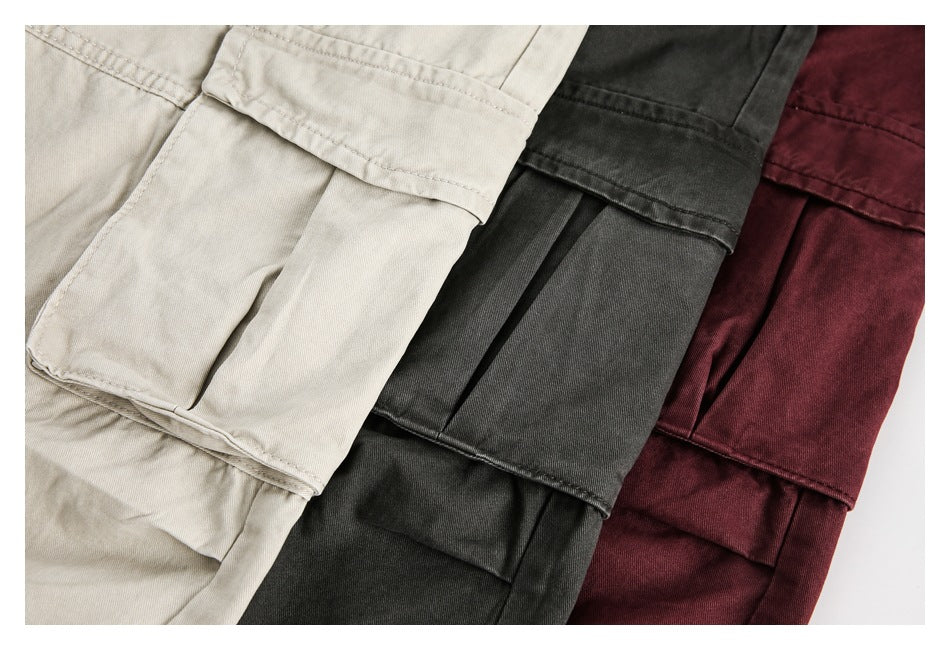 Close-up of cargo pockets on beige, charcoal, and burgundy trousers arranged side by side.