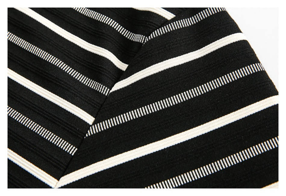 Close-up of a seam in black fabric patterned with cream and narrow white stripes.