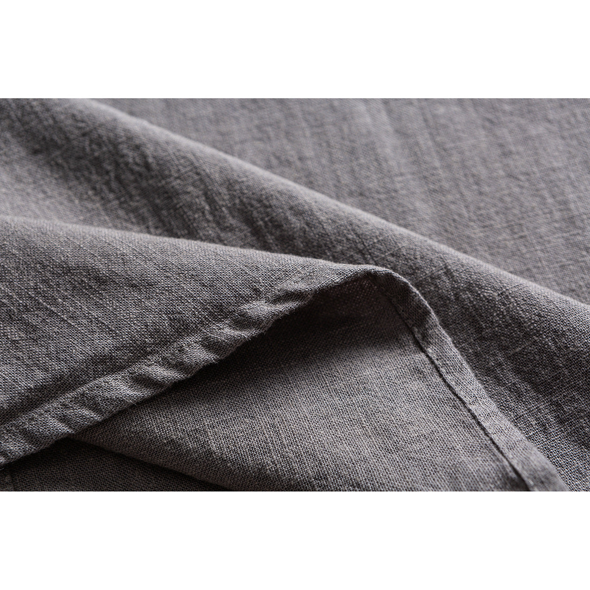 Close-up of textured gray shirt fabric folded to show its weave and seam.
