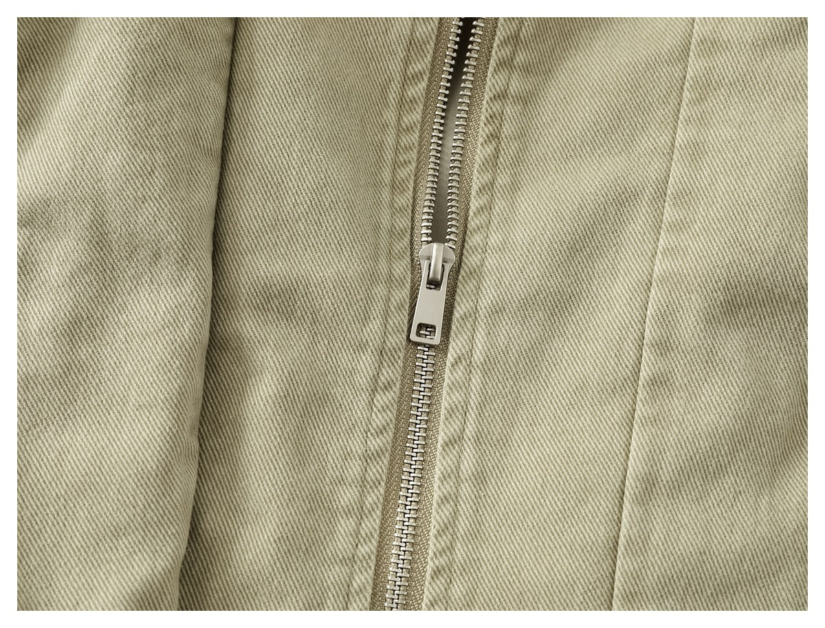 Close-up of a metal zipper on light khaki twill fabric.