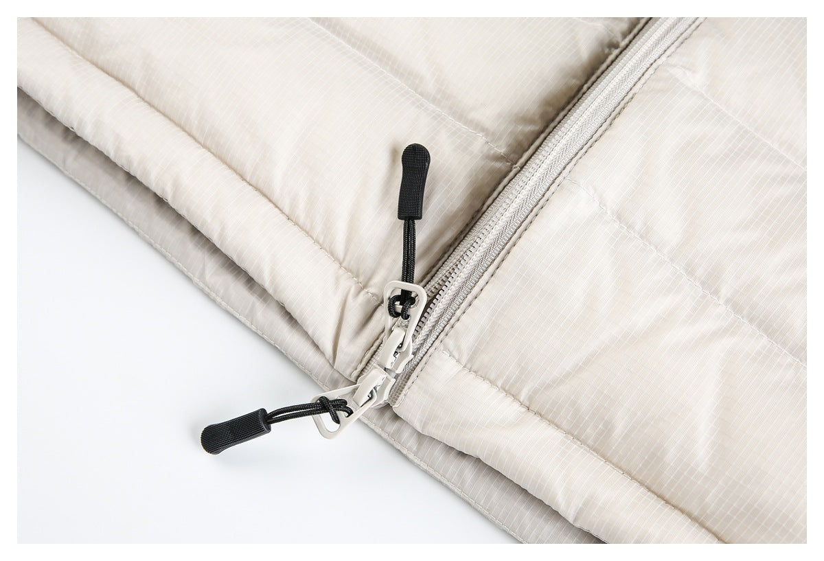 Close-up of two zipper pulls with black cord tabs on the off-white jacket.