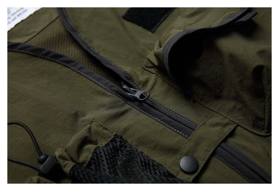 Close-up of the olive vest's front zipper, mesh pocket, snap tab and flap pocket.