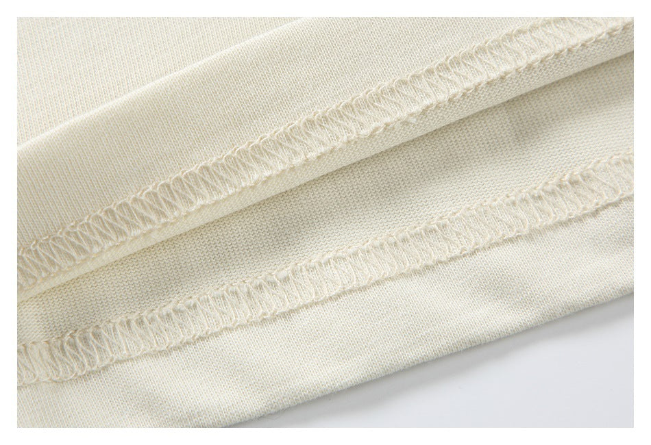 Close-up of cream fabric showing two overlocked seam finishes.