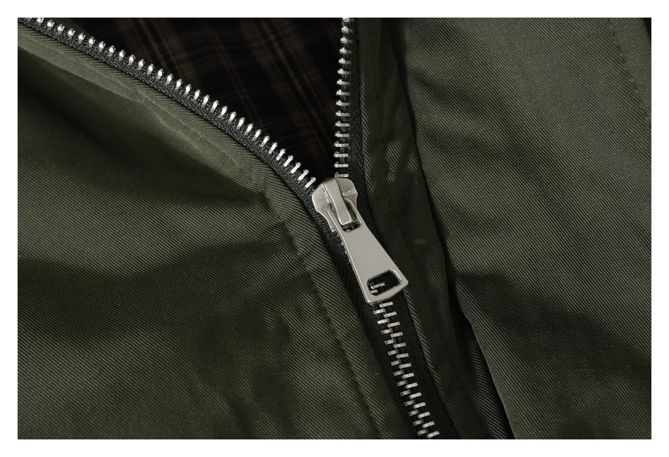 Close-up of the olive jacket's silver front zipper and plaid lining.