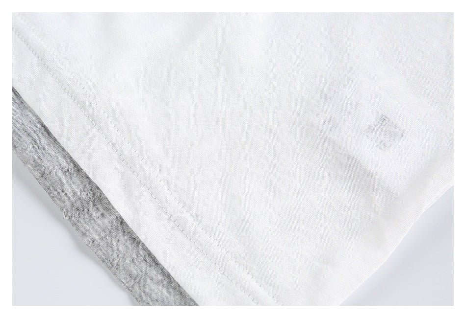 Close-up of white garment fabric with a diagonal stitched seam and gray fabric visible underneath.
