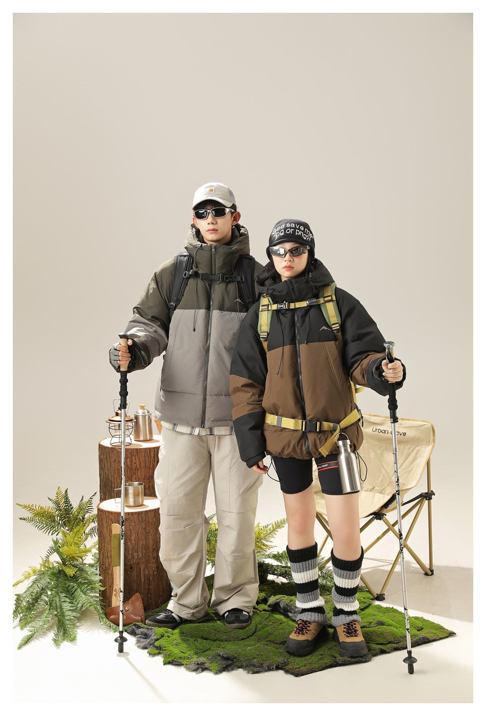 Two models wear color-block hooded puffer jackets, one olive and gray, the other black and brown, in a camping scene.