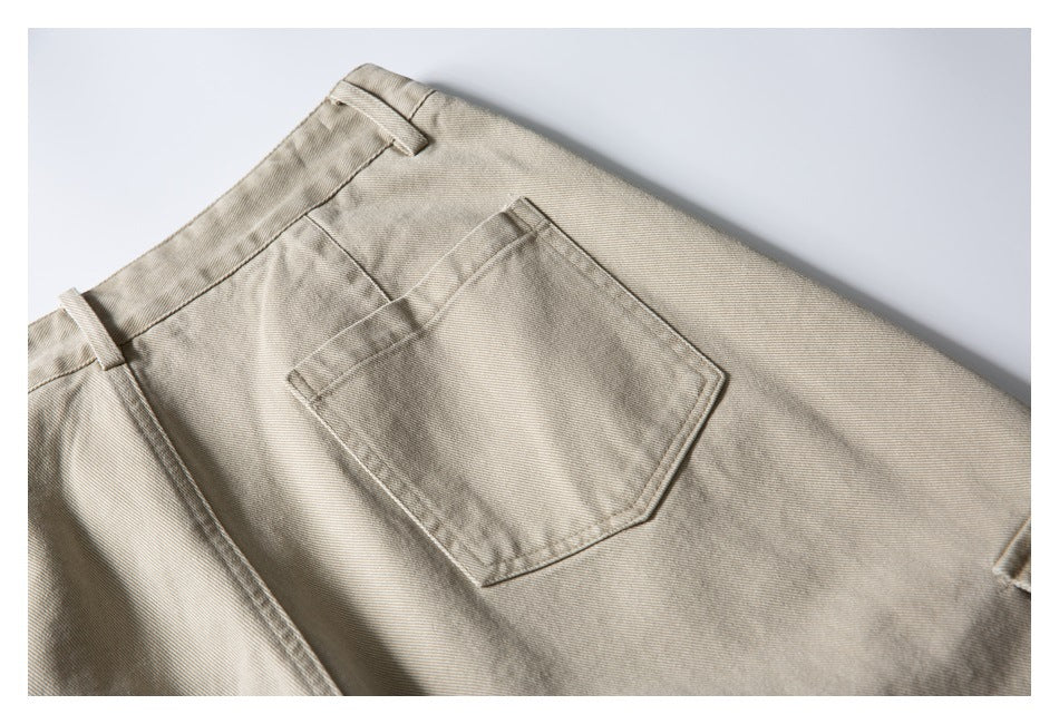 Close-up of beige trousers with a stitched rear pocket and waistband on a light background.