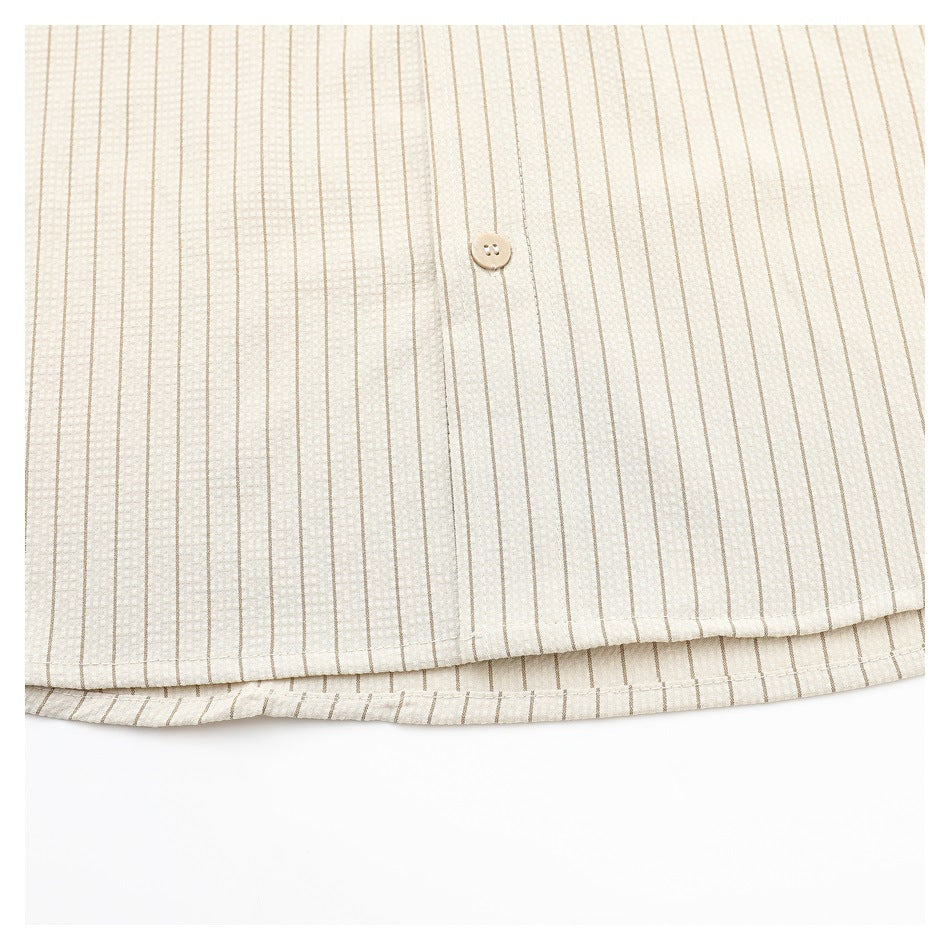 Close-up of the cream shirt's striped lower hem and front button.