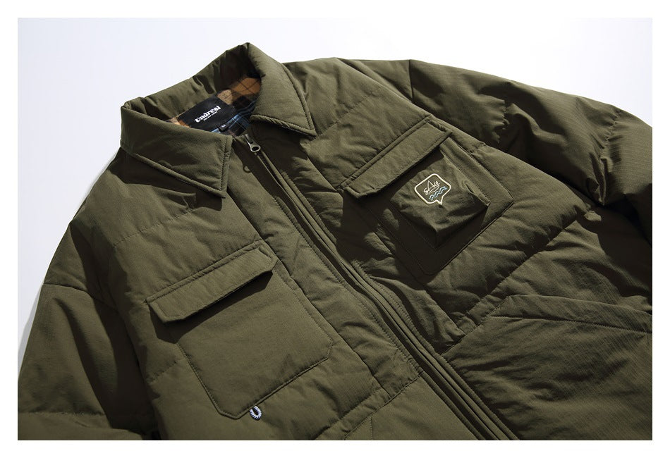Close-up of an olive quilted jacket showing its collar, zipper, flap pockets, and chest patch.