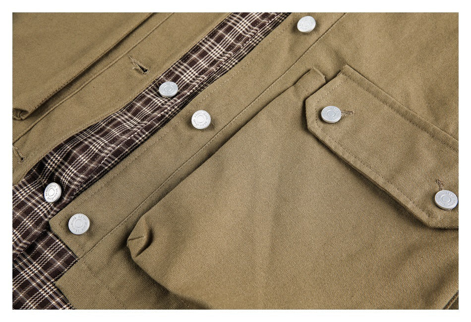 Close-up of a khaki jacket front with silver buttons, a flap pocket, and brown plaid lining.