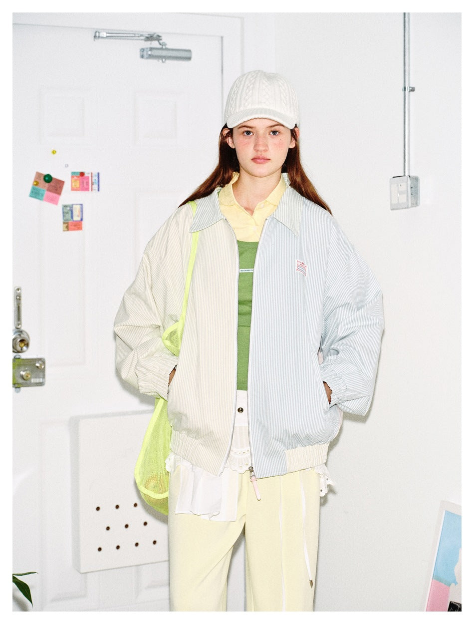 Front view of a model wearing an oversized pastel pinstriped zip jacket with a wide collar.