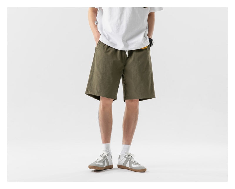 Front view of a model wearing olive green drawstring shorts and a white T-shirt.