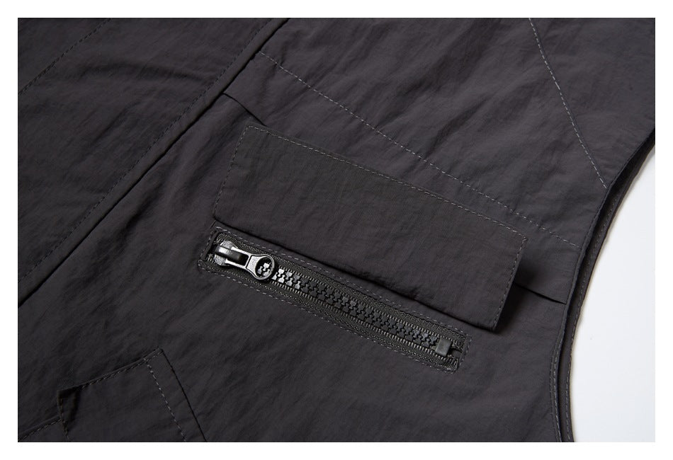 Close-up of a dark charcoal garment panel with a horizontal zip pocket and stitched flap.