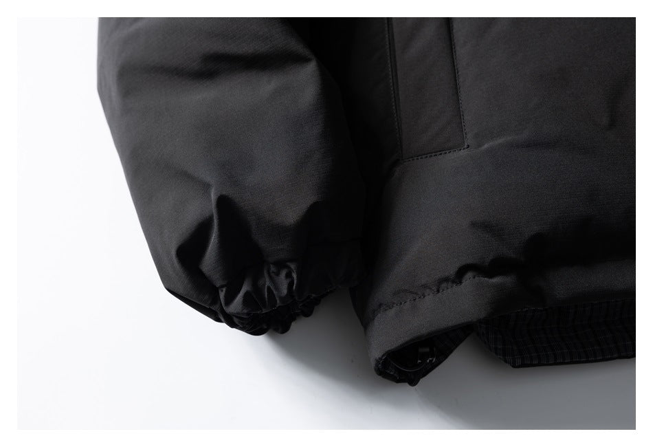 Close-up of a black jacket sleeve with an elasticated cuff and hem; dark plaid lining peeks out below.