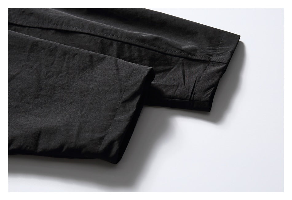 Close-up of a black sleeve cuff and hem stitching against a white background.