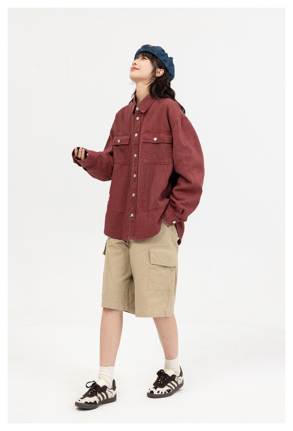 Full-length view of a model in a muted red utility overshirt with buttoned chest pockets and beige cargo shorts.