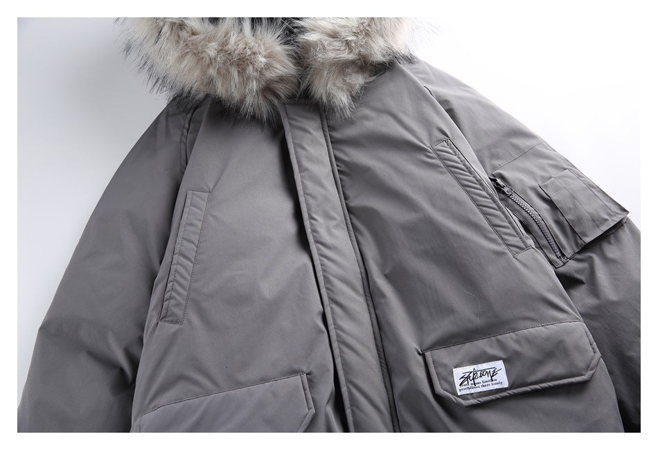 Close-up of a charcoal-gray jacket front with flap pockets, a sleeve zipper pocket, and a fur-trimmed hood.