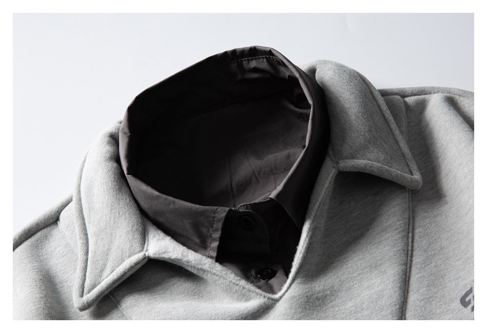 Close-up of a light gray sweatshirt's pointed collar layered over a black button-up shirt.