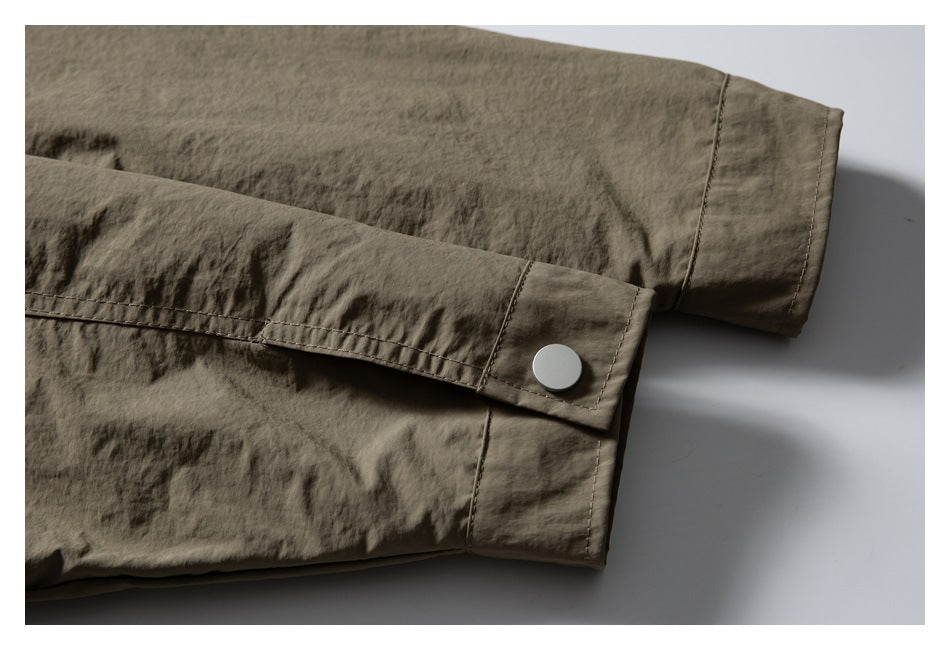 Close-up of olive-brown jacket sleeves with cuff tabs, stitching, and a metal snap.