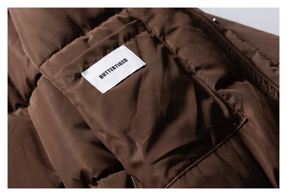 Close-up of a sewn white BUTTERTIGER label on brown jacket fabric beside the zipper.