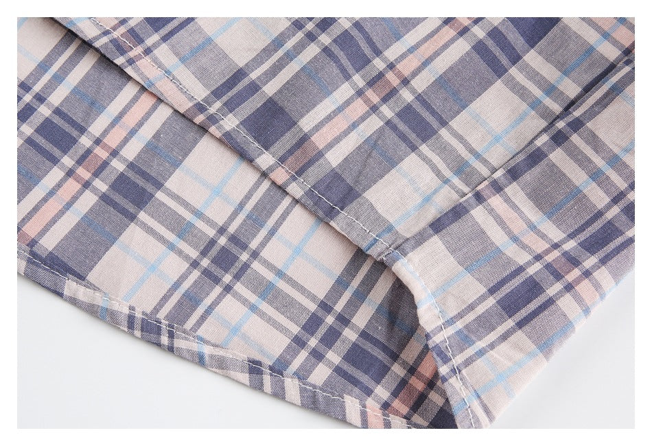 Close-up of a garment hem and seam in a beige, navy, gray, and pale blue plaid.
