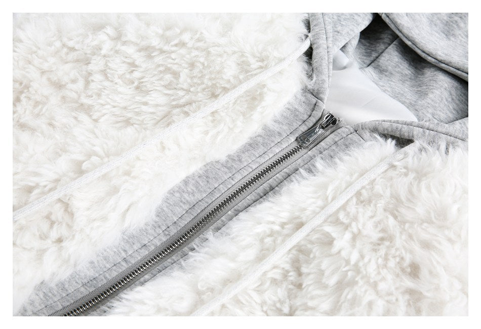 Close-up of a white fluffy hooded jacket with gray trim, a metal zipper, and white drawstrings.