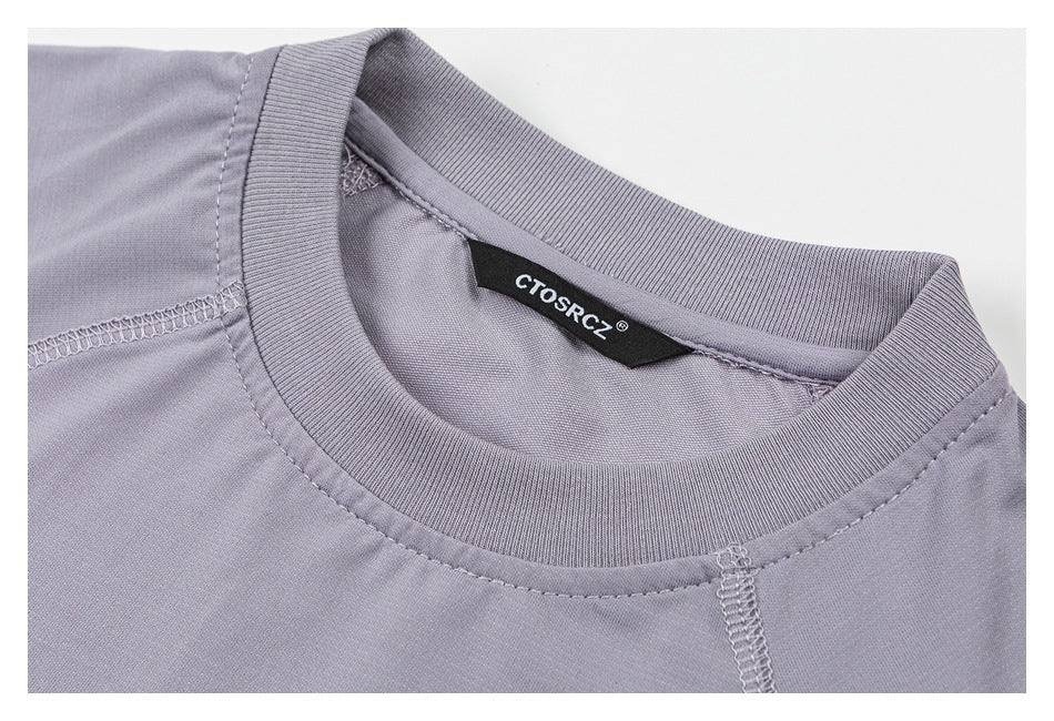 Close-up of a lavender-gray crew neck with ribbed collar, stitching, and a black sewn-in brand label.