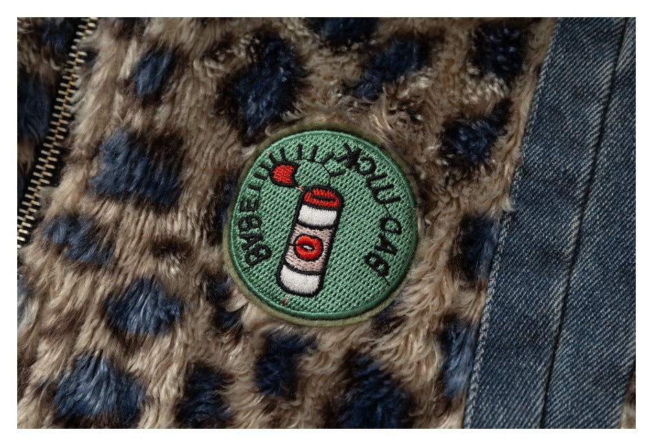 Close-up of an embroidered green patch on the jacket's spotted plush panel beside a denim seam.