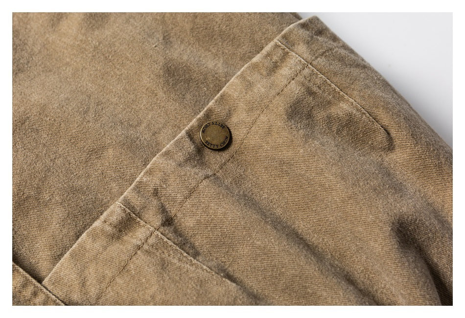 Close-up of a tan garment seam and button with small lettering.