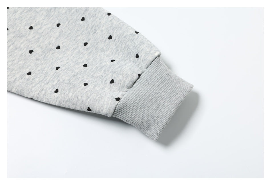 Close-up of a ribbed cuff on a light gray sleeve scattered with small black hearts.
